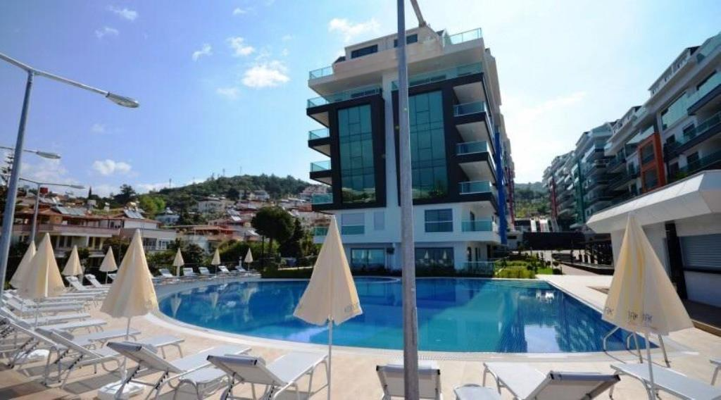 Outdoor pool with white umbrellas and loungers for residents of apartments in a complex in Turkey