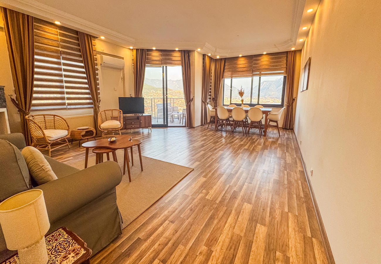 Open-plan kitchen and living room with a corner sofa and panoramic windows in a flat in Alanya