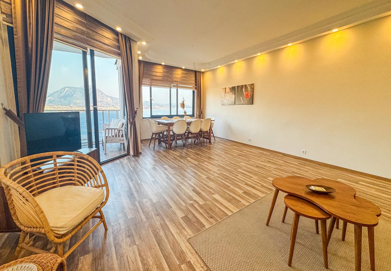 Living room with a wicker armchair, television and panoramic glazing in a residence in Türkiye