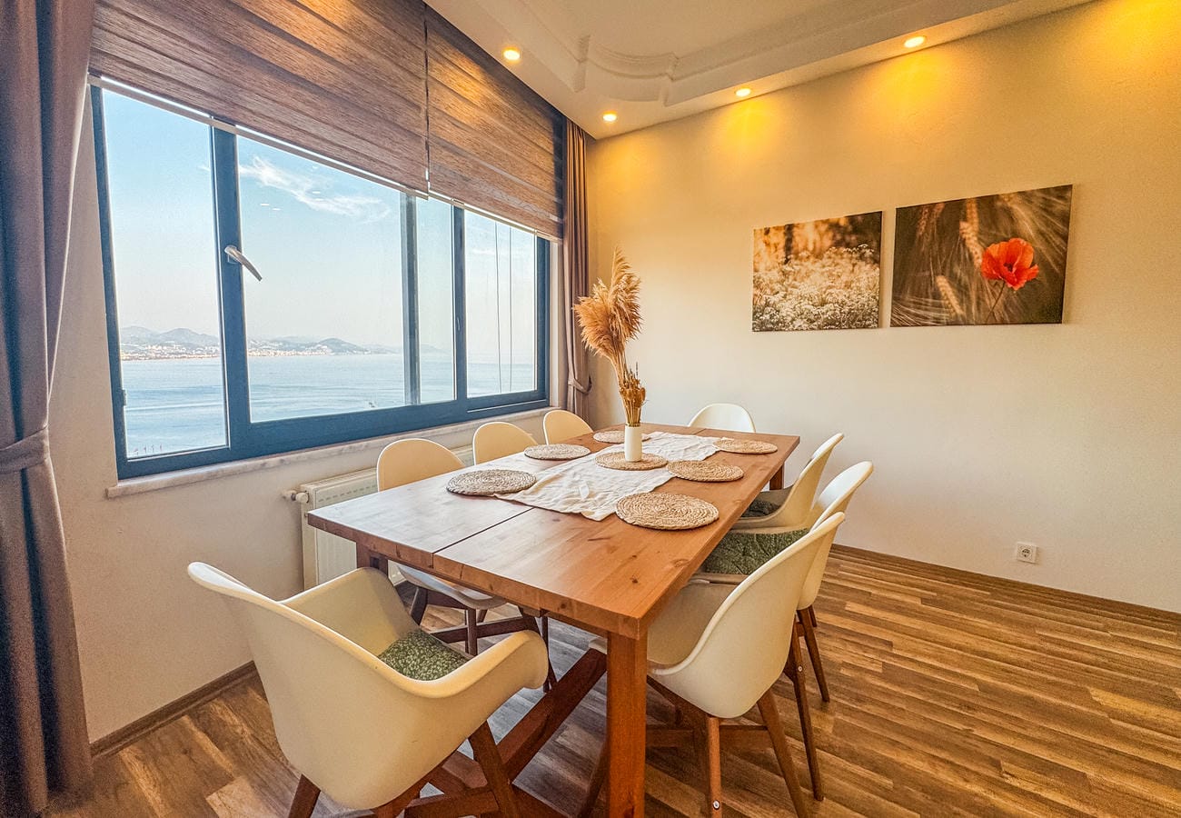 Dining room with a wooden table, six chairs and sea and mountain views in an apartment for sale in Alanya