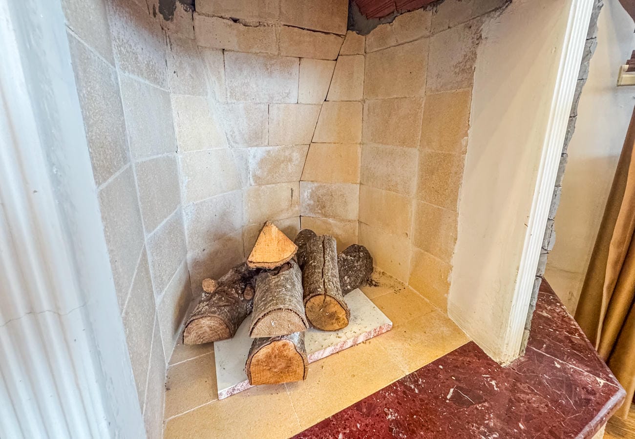 Living room fireplace niche with logs, marble mantel and stone cladding