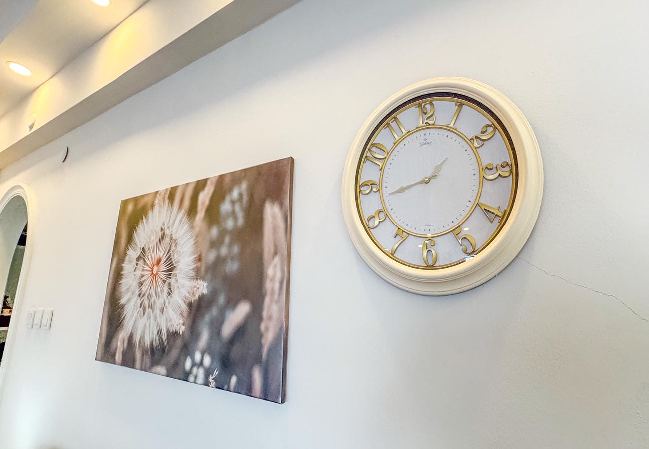 Living room wall clocks and a dandelion painting beside an arched doorway in a residence in Alanya