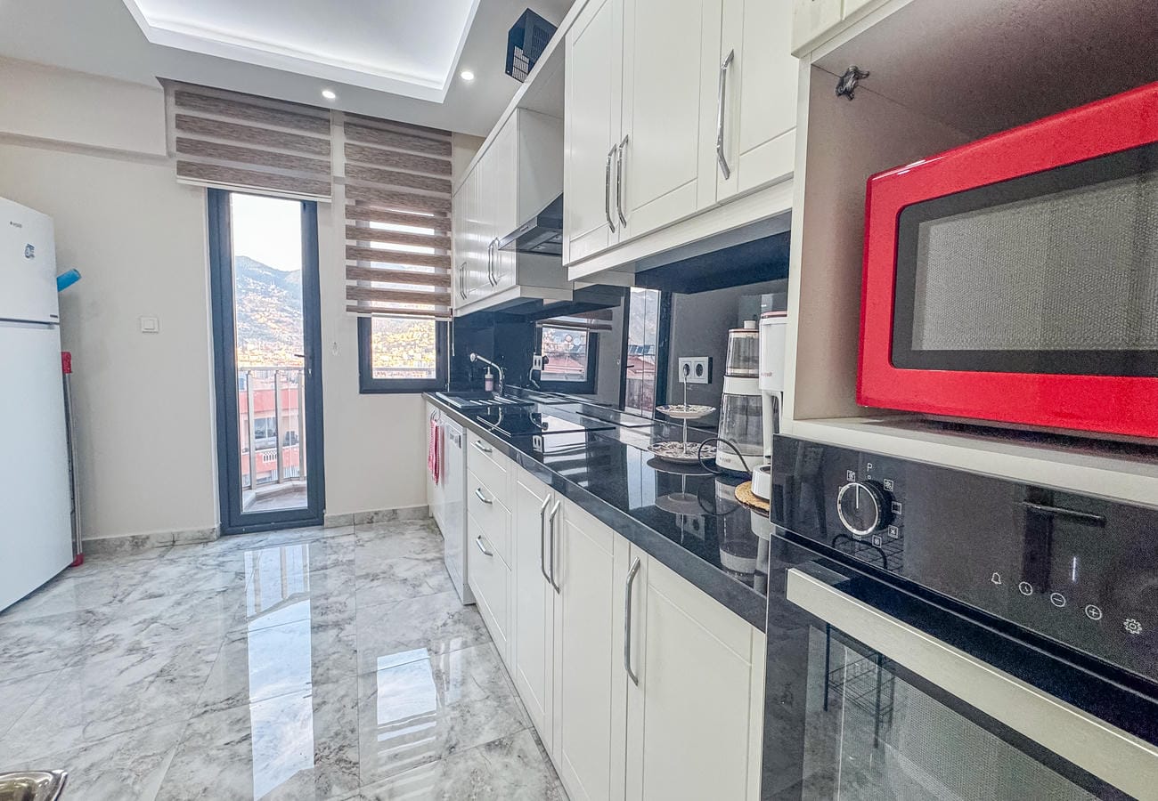 Kitchen with white cabinets, black worktop and built-in appliances in an apartment