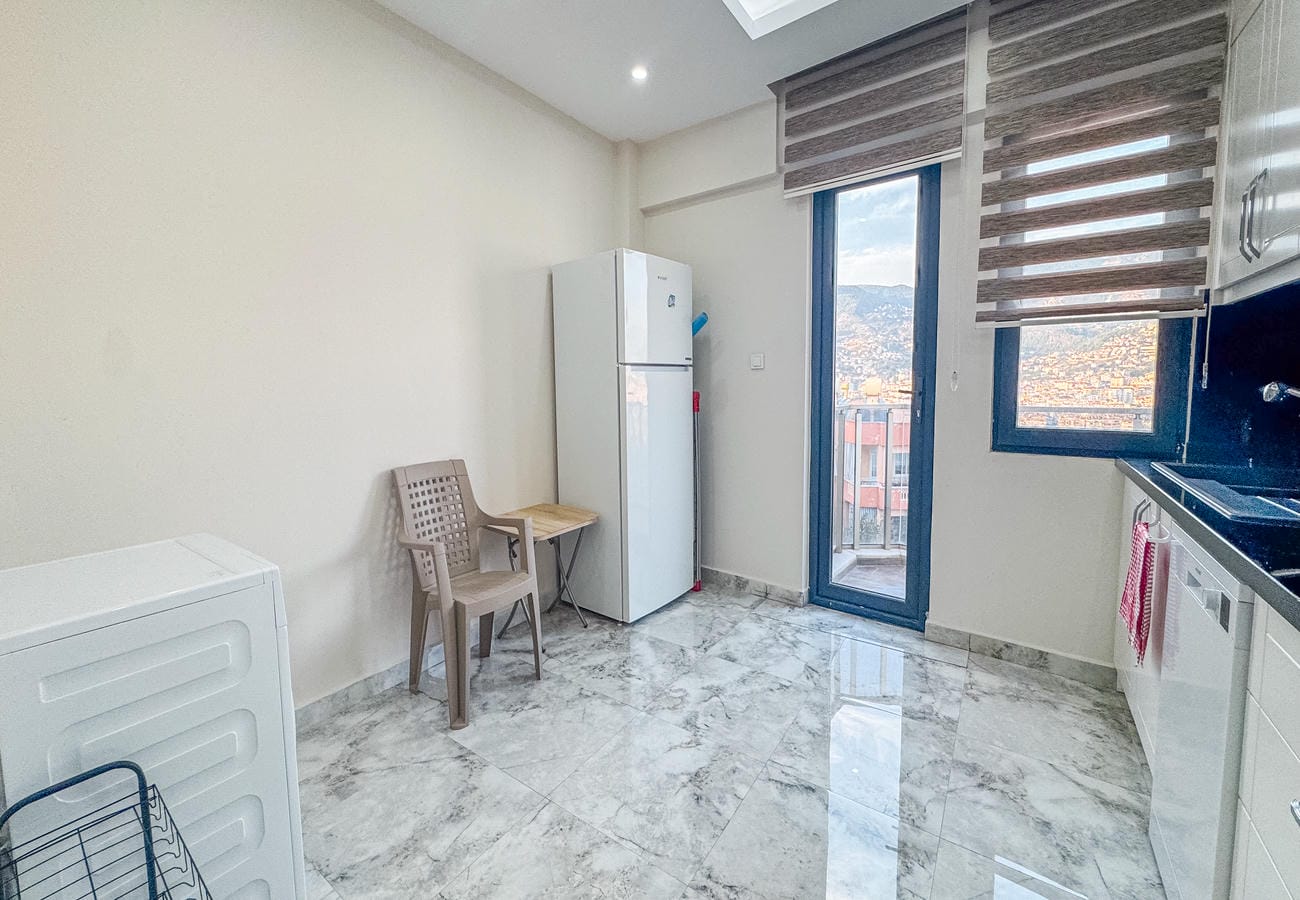 Kitchen with a white refrigerator, washing machine and black worktop in Alanya