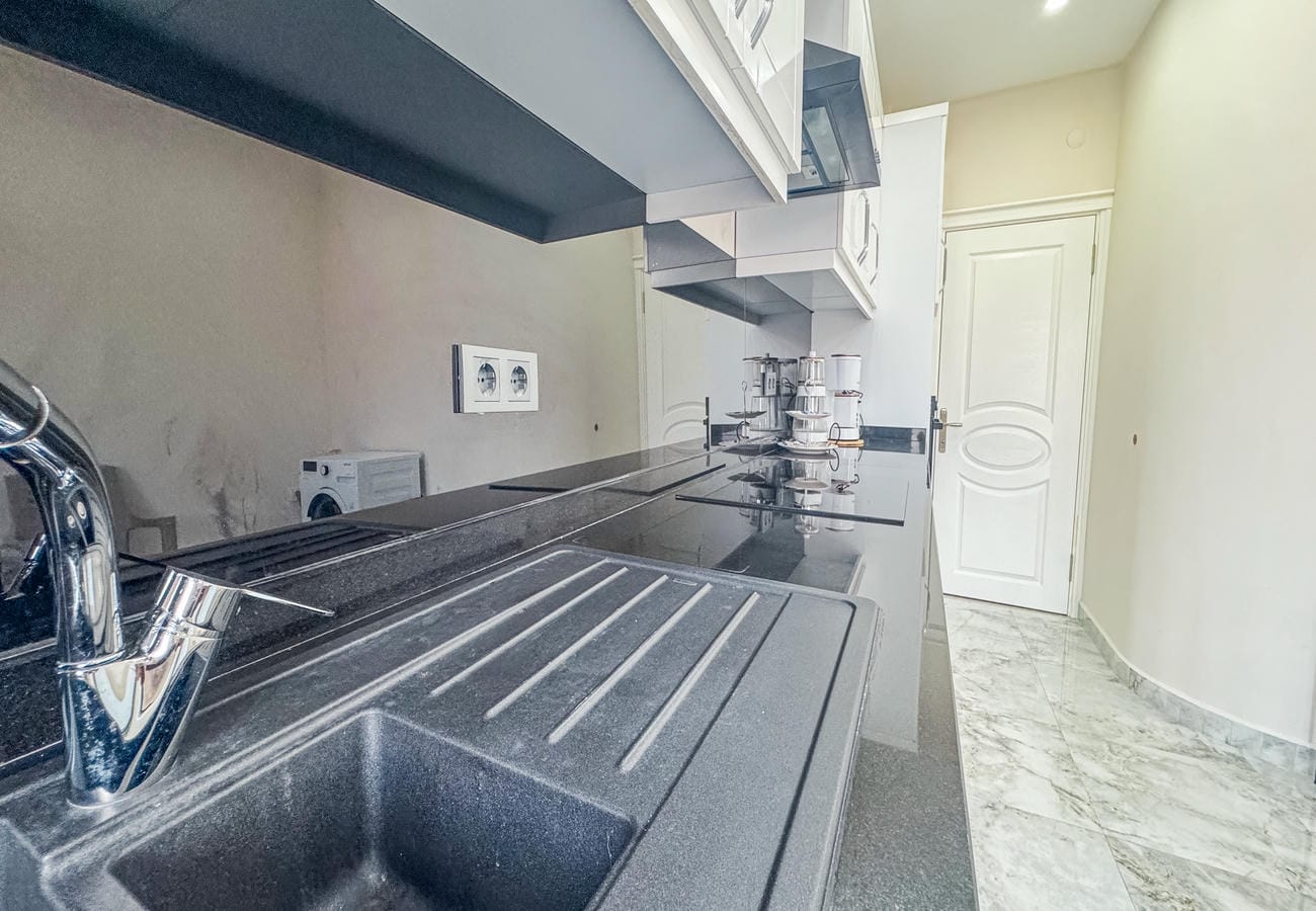 Kitchen with a granite sink, black worktop and white wall cabinets in a flat
