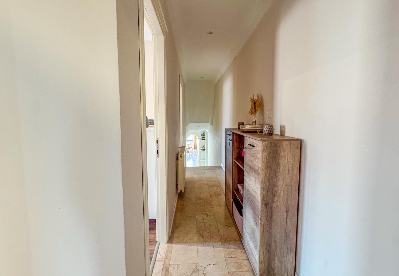 Bright hallway with marble flooring, wooden chest and an arched doorway