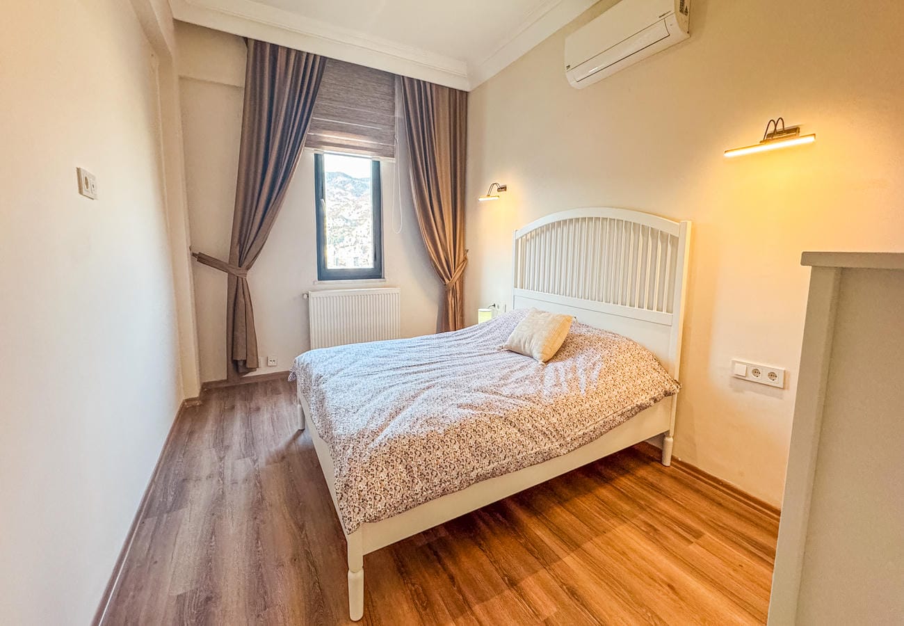 Bedroom with a double bed, brown curtains and wall lights in an apartment in Alanya