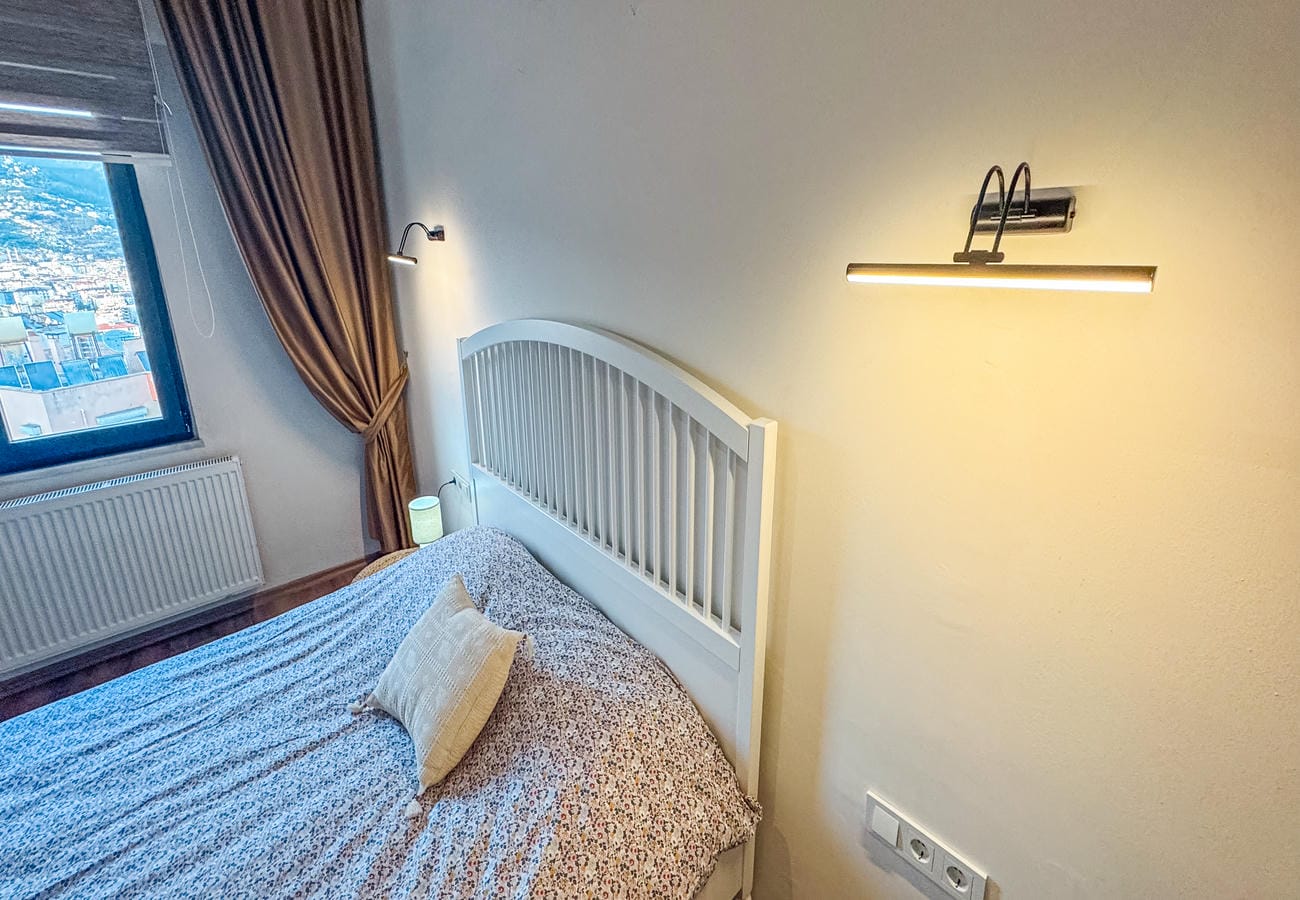 Bedroom with a bed beside a window overlooking the city in Alanya