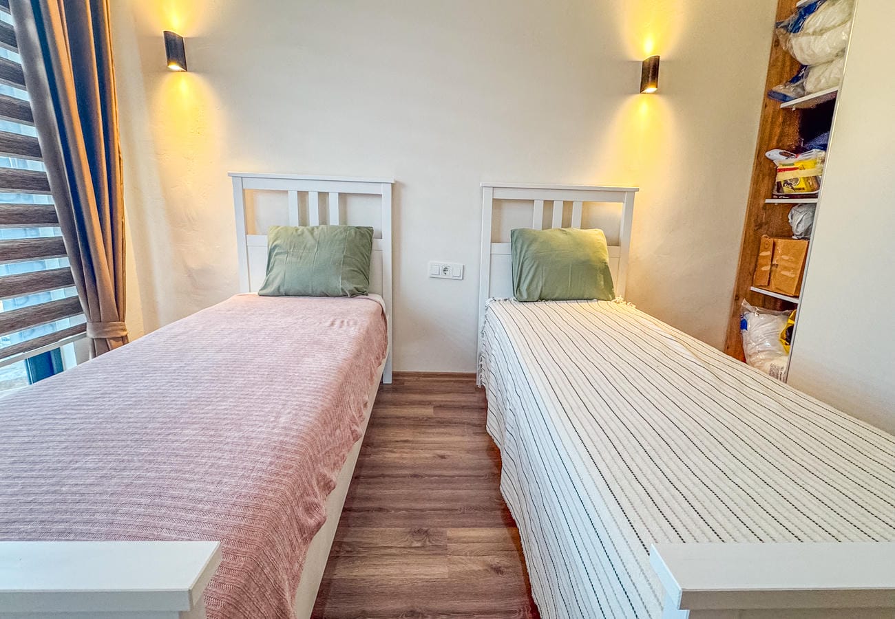 Bedroom with two single beds, pink covers and an open shelving unit in a flat in Alanya