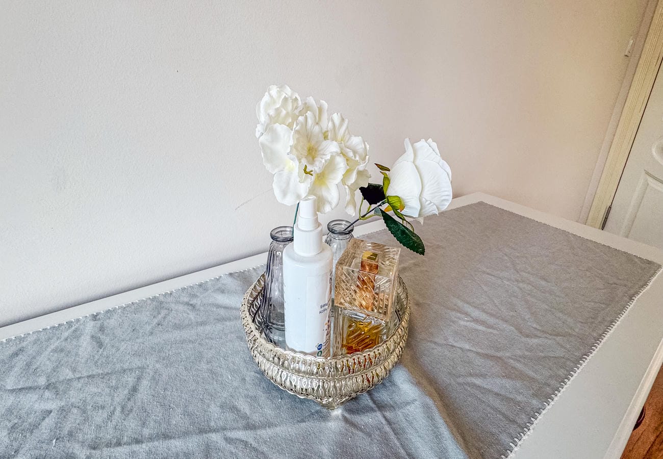 Decorative tray with white orchids and a glass bottle on a bedroom chest