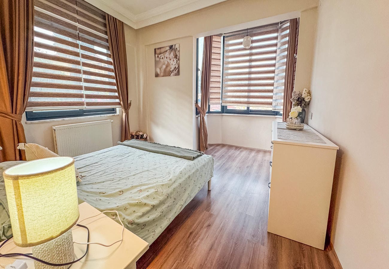 Bedroom with a double bed, twin window and white chest in a flat