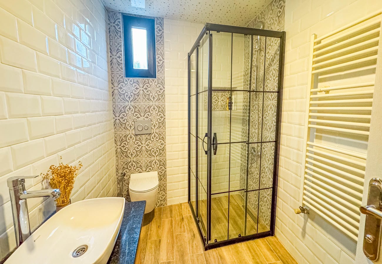 Bathroom with glass shower enclosure, white basin and decorative tile in an apartment