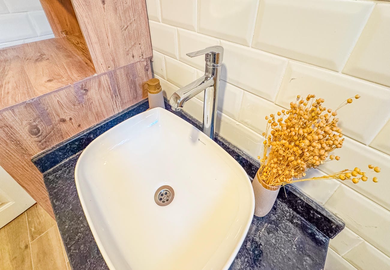 Bathroom with white vessel sink, stone worktop and dried flowers in Alanya