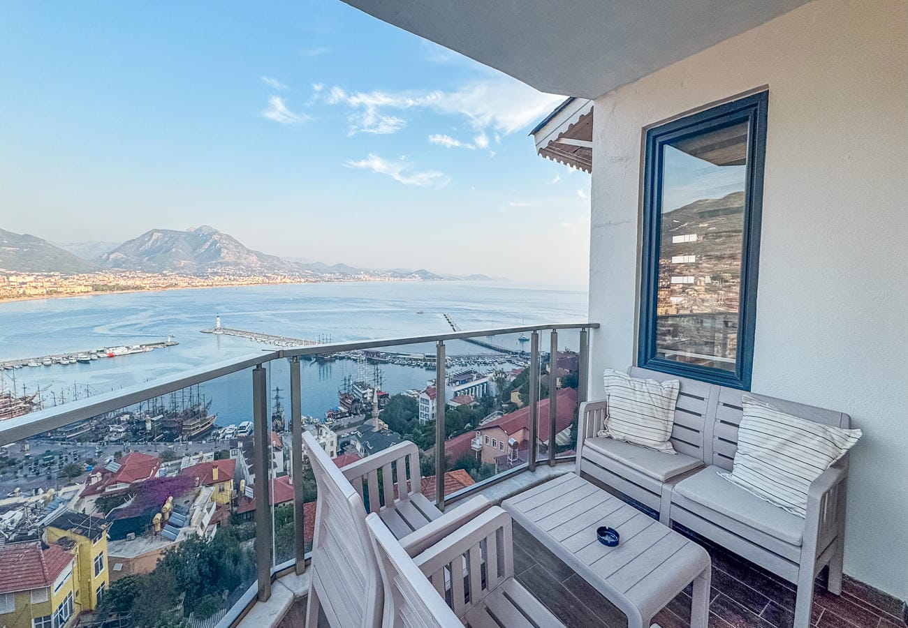 Balcony with glass railing and outdoor furniture overlooks the harbor in Türkiye