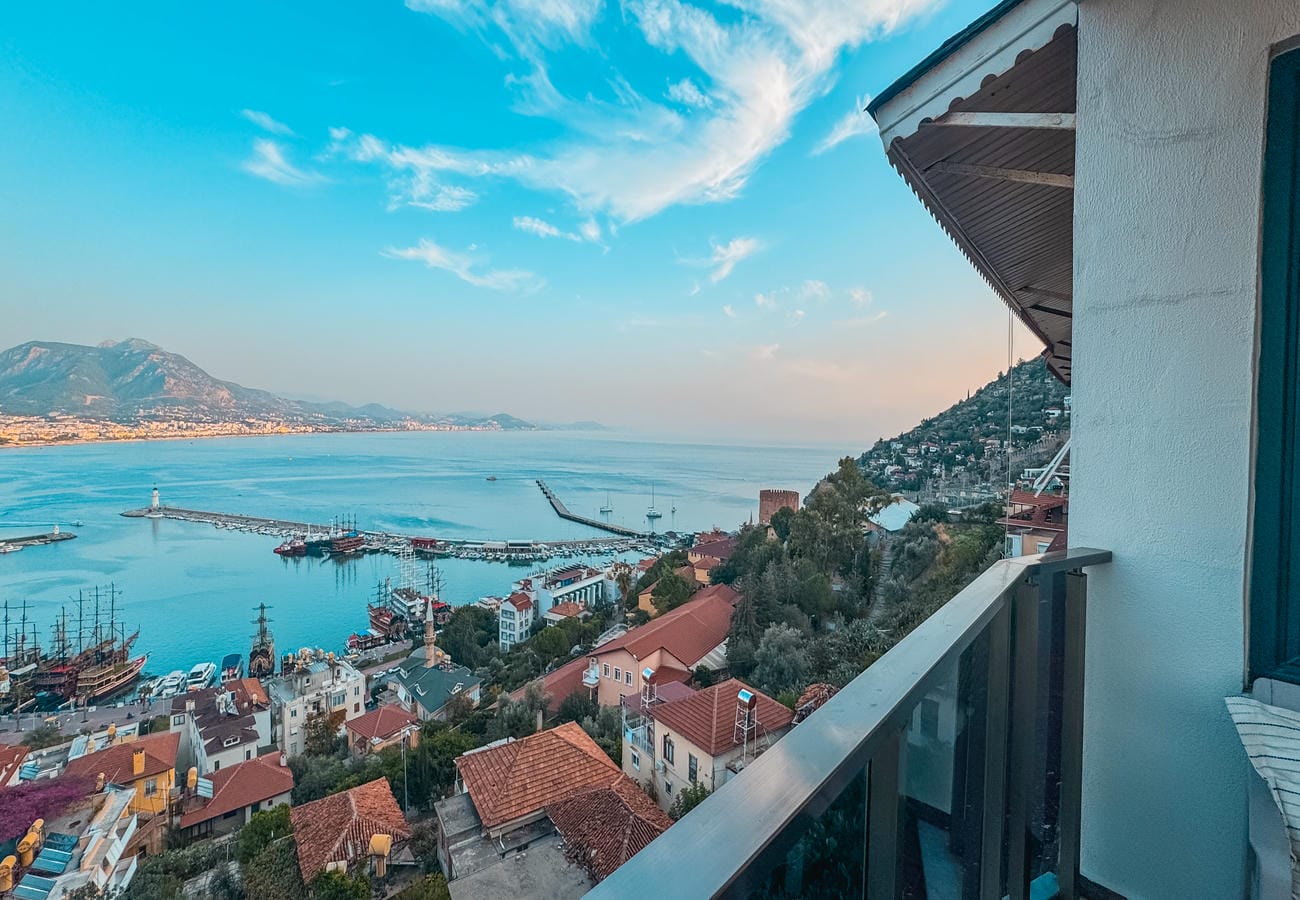 Panoramic sea bay with port piers and hillside cityscape shows a residence for sale in Alanya