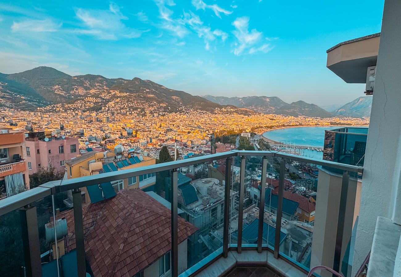 Bay panorama with mountain range and port through a glass balcony railing in Alanya, Türkiye
