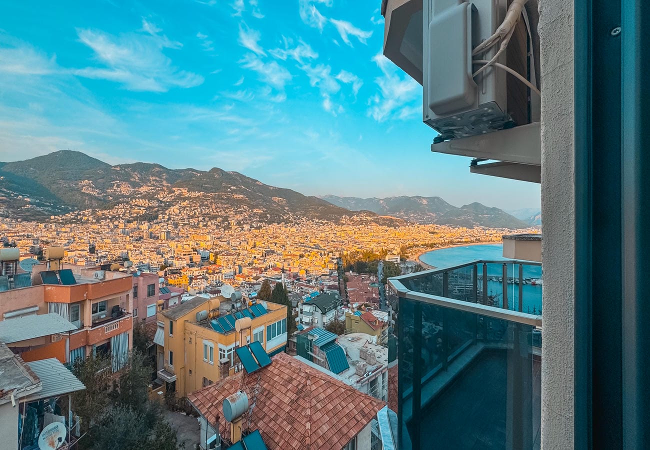 Panoramic mountain city and bay beyond a glass balcony railing in a flat