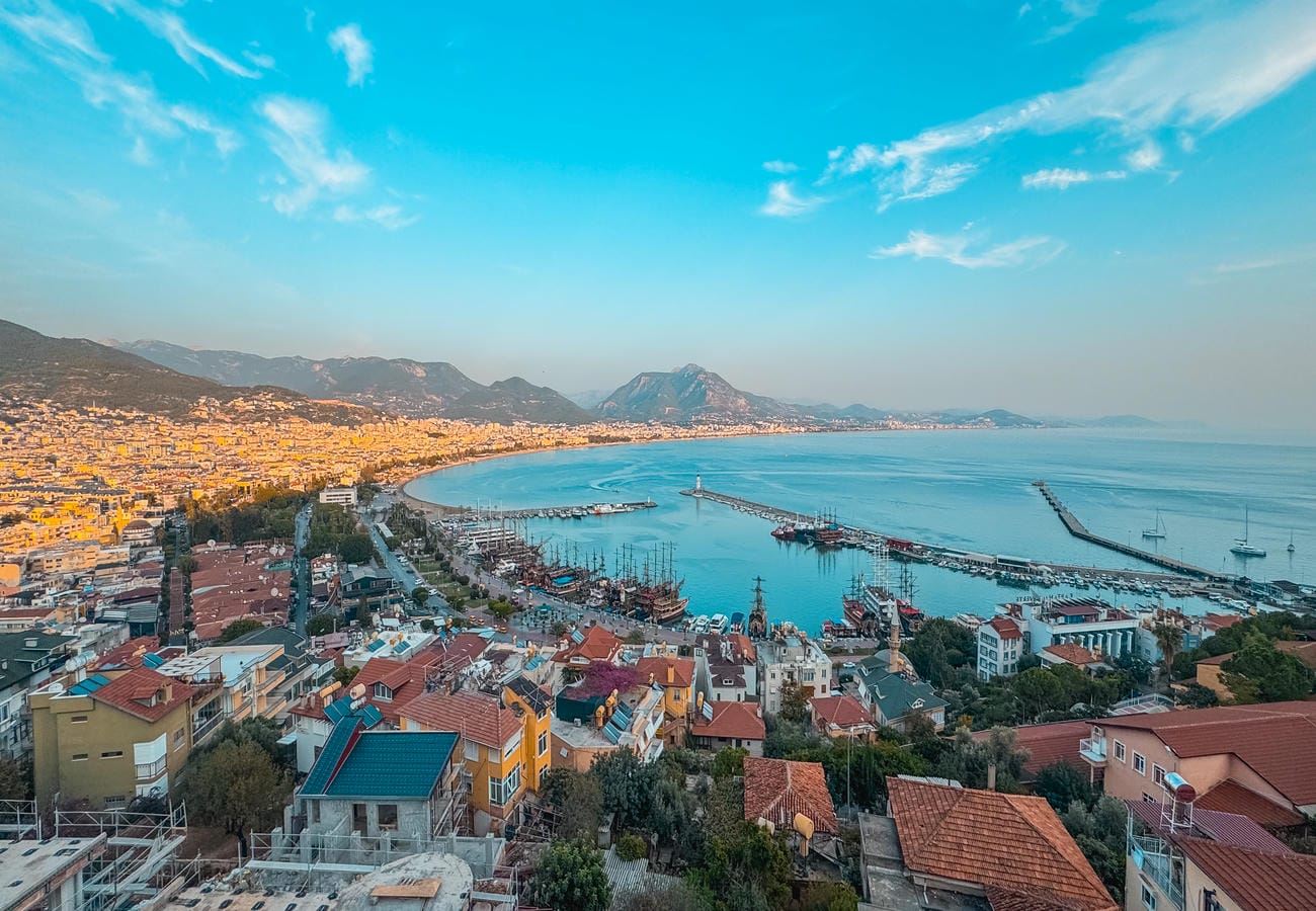 Wide sea bay with yacht piers, mountain range and colorful roofs surrounds a flat in Alanya