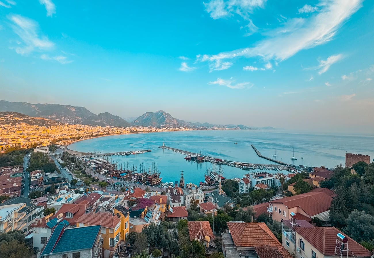 Wide sea bay with long harbor breakwaters and mountain ridge by a complex with apartments for sale