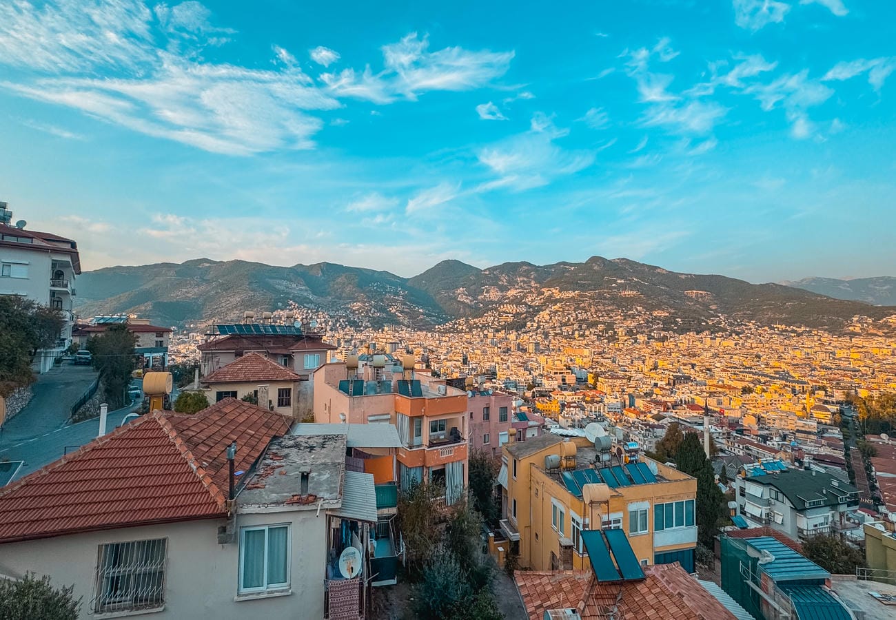 Panoramic mountain view over dense city blocks with tiled roofs and blue awnings in Turkey