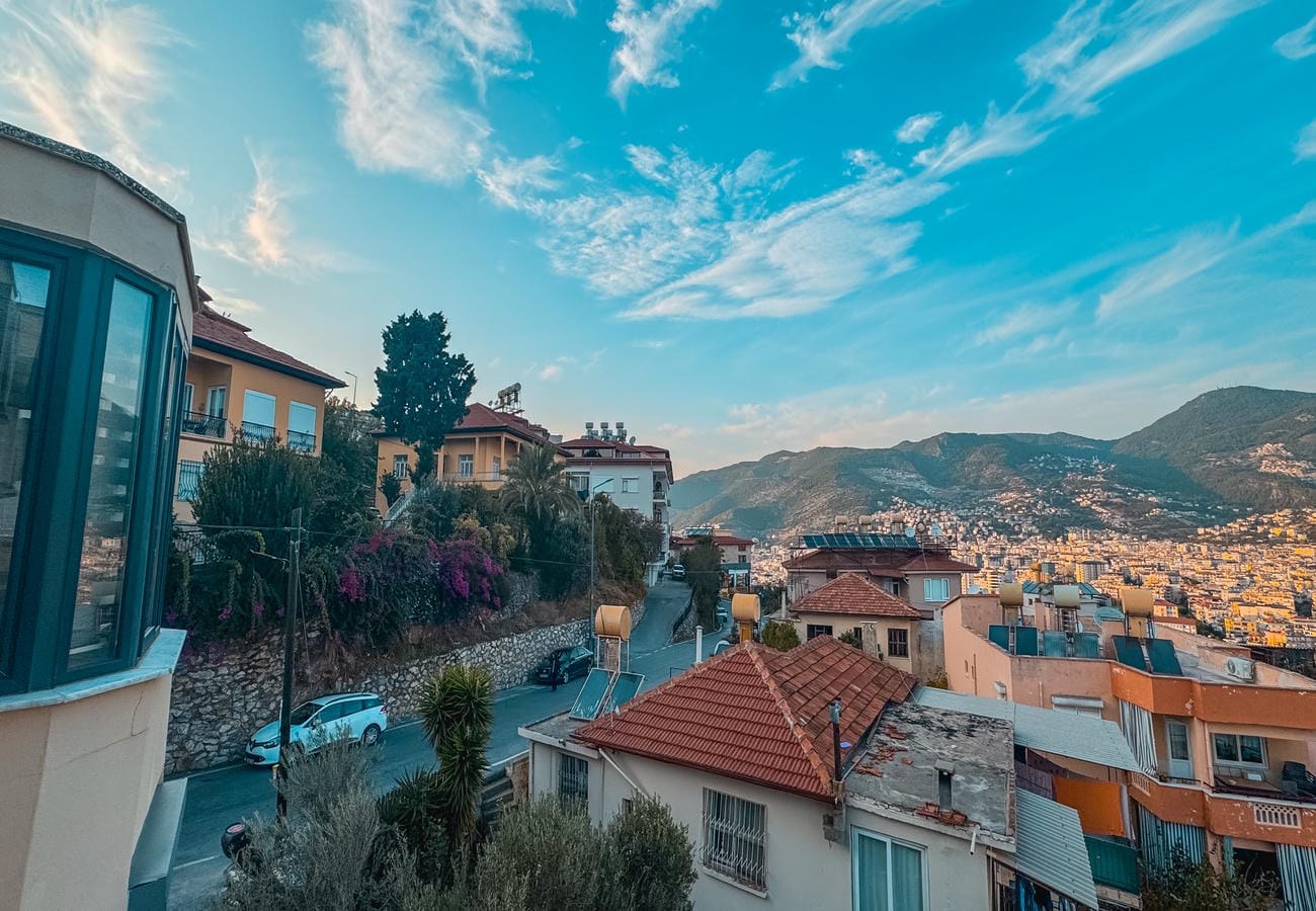 Hillside cityscape with red tile roofs and a winding street where apartments are for sale