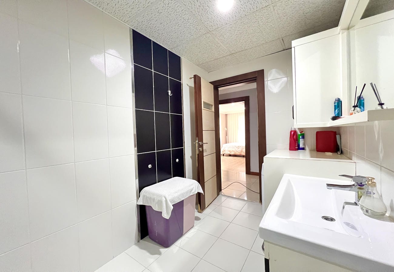 Beyaz lavabolu banyo 4+1 dairede ayna ve siyah dekoratif fayansla birlikte yer alıyor