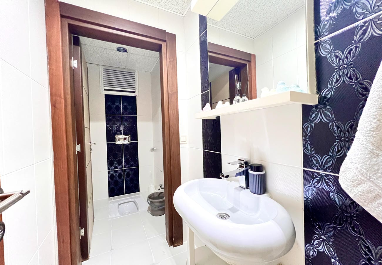 Beyaz lavabolu banyo Çikcilli’de duş bölümü ve siyah beyaz duvar fayanslarıyla görülüyor