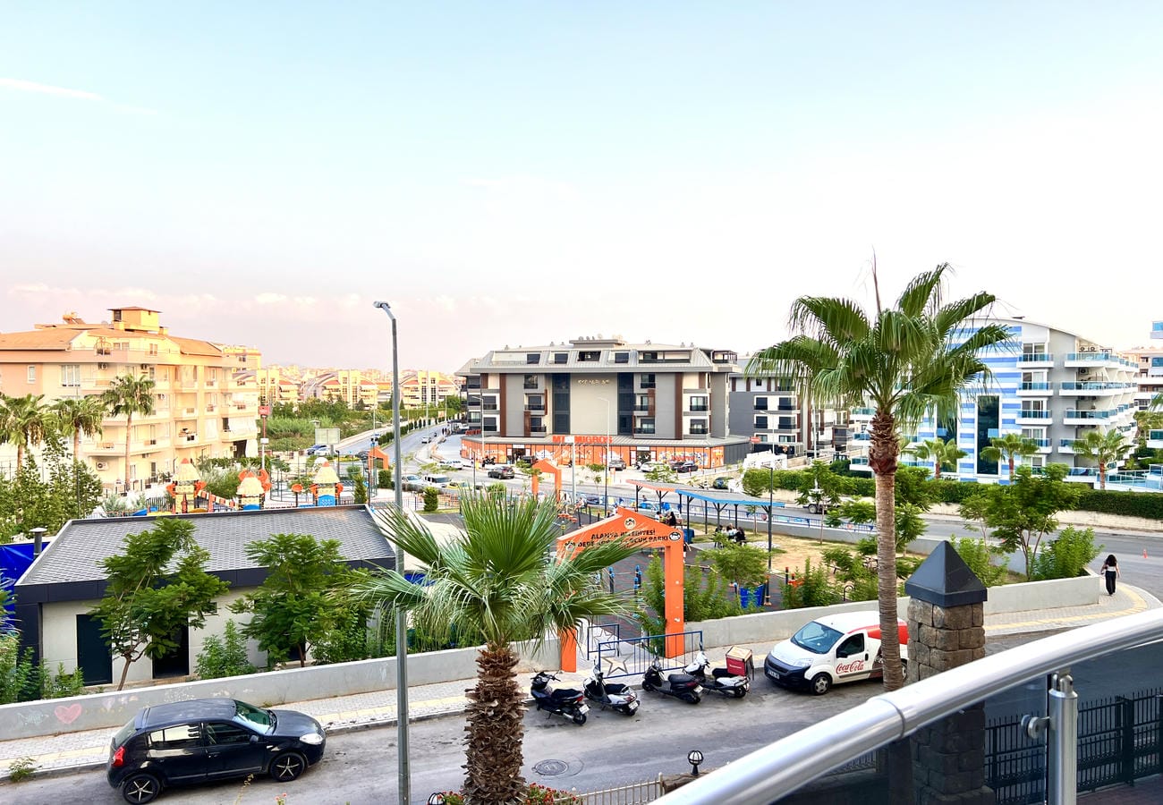 Palmiyeli şehir yolu ve çocuk oyun alanı Çikcilli’de Türkiye’deki konutların önünde görülüyor