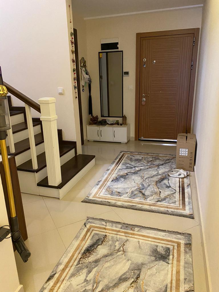 Alanya’daki giriş holünde ayna, beyaz konsol ve koyu basamaklı iç merdiven