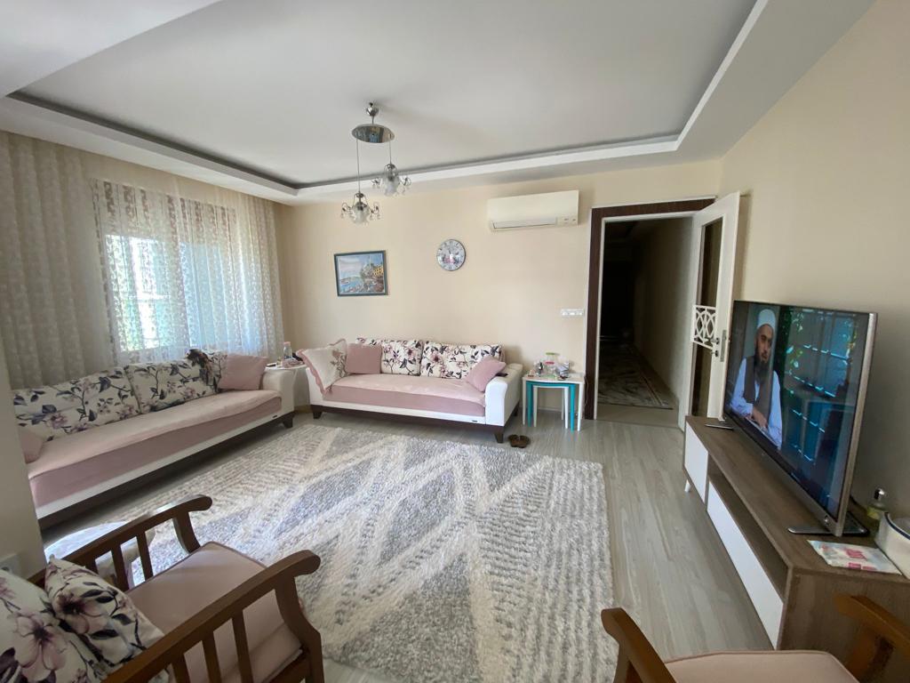 Çiçek desenli koltuklu salonda Türkiye’de satılık penthouse için büyük televizyon ve aydınlık halı