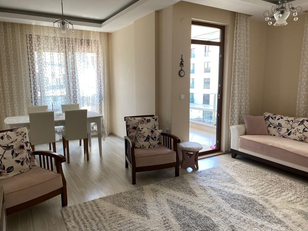Panoramik camlı salonda Türkiye’de satışta olan dairenin köşe kanepesi ve yemek masası