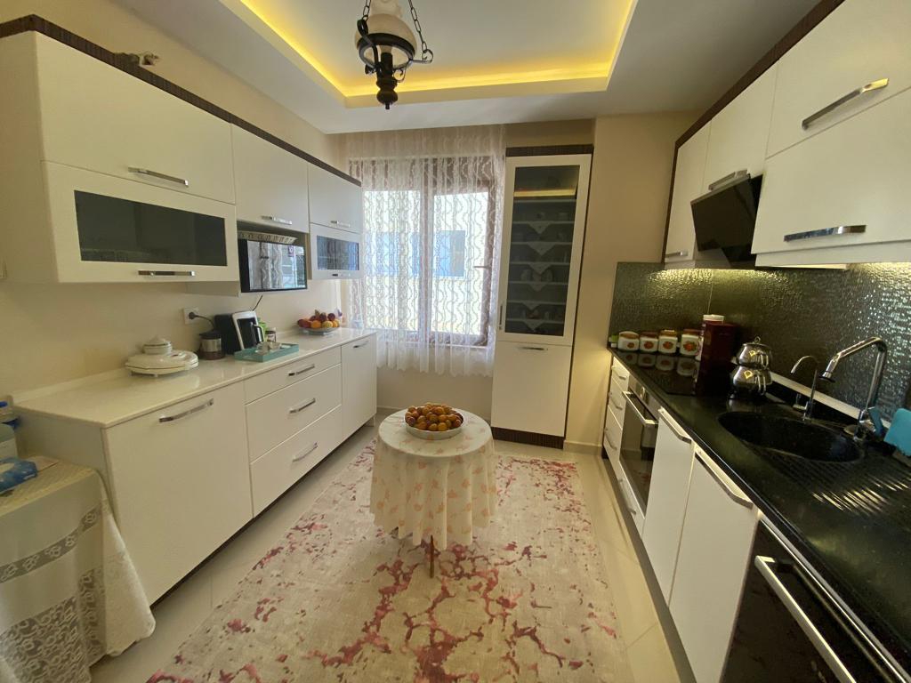 Siyah tezgâhlı beyaz mutfakta Alanya’daki penthouse için mozaik backsplash ve ankastre fırın