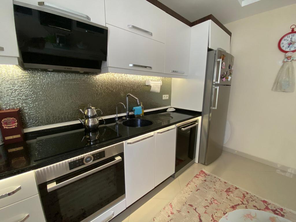 Siyah davlumbazlı beyaz mutfakta penthouse için aydınlatmalı mozaik backsplash ve ankastre fırın