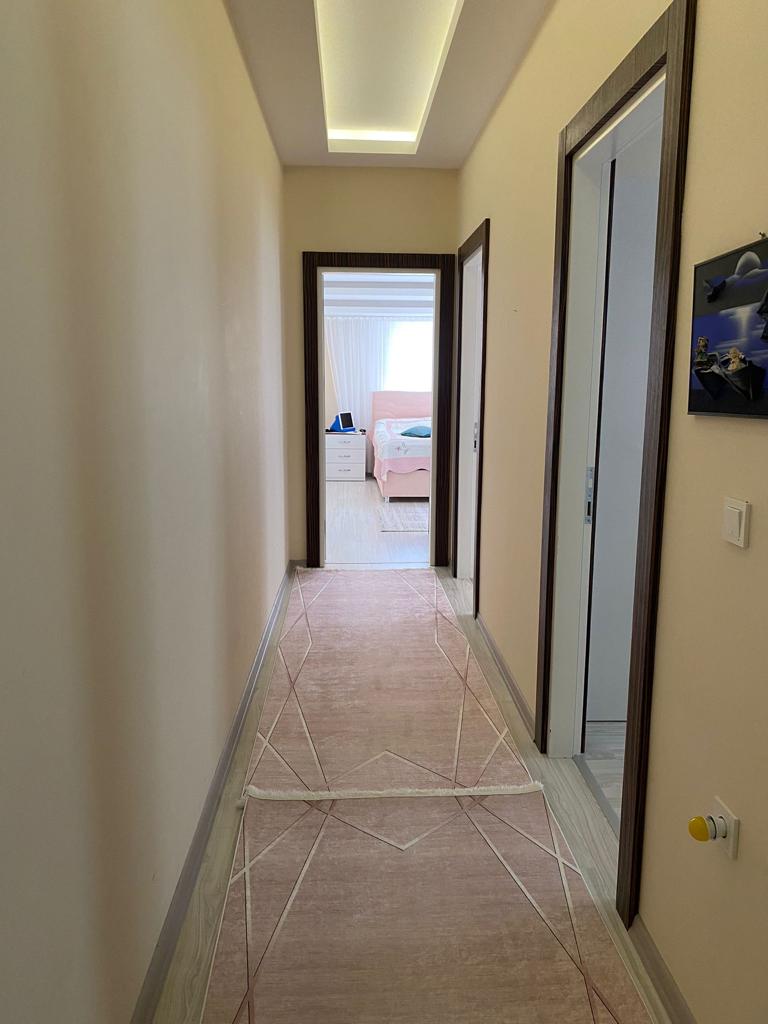 Geometrik zeminli koridorda penthouse için aydınlatmalı katmanlı tavan ve oda kapıları