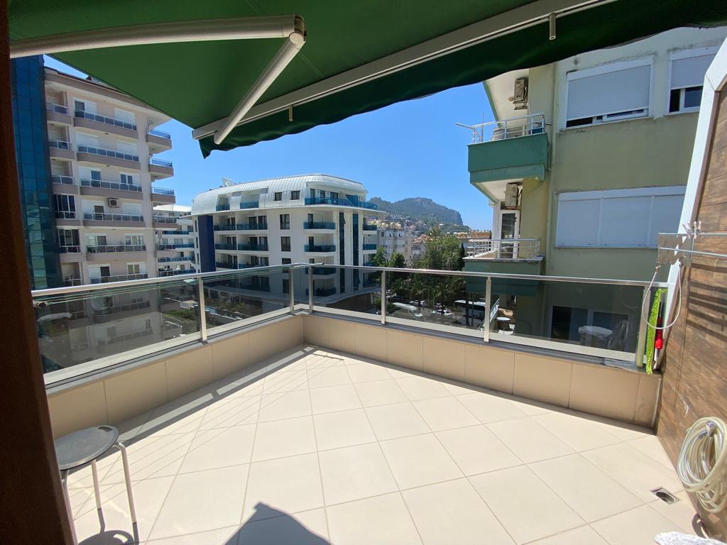 Dağ yamacına bakan köşe terasta Türkiye’de satılık penthouse için cam korkuluk ve yeşil tente