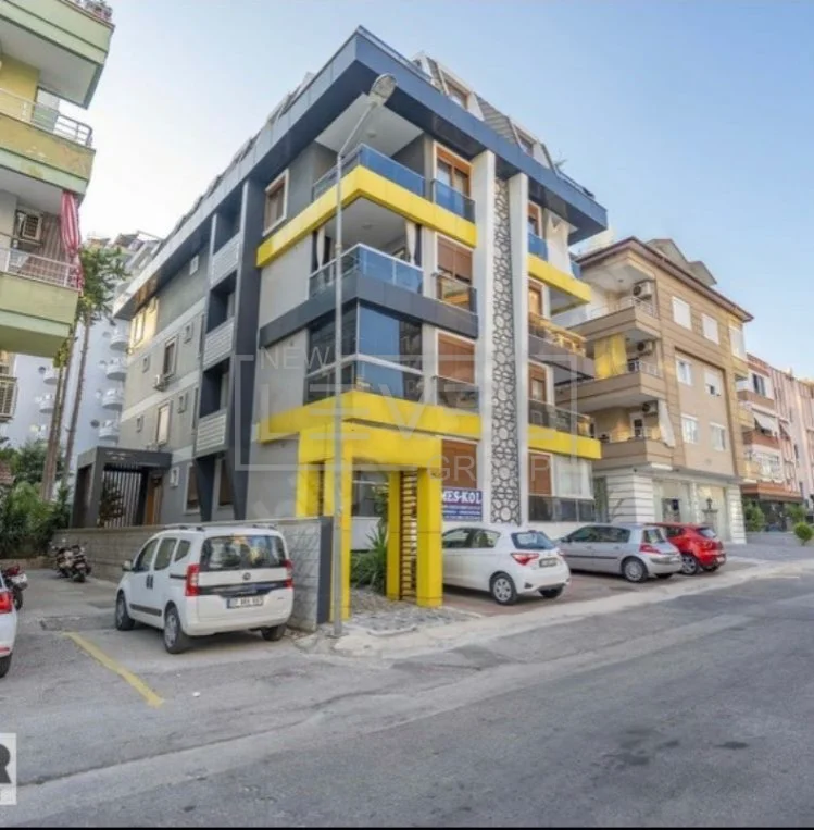 Gri cepheli ve sarı balkon şeritli bina önünde 3+1 penthouse Alanya’da Türkiye’de satışta — New Level Group