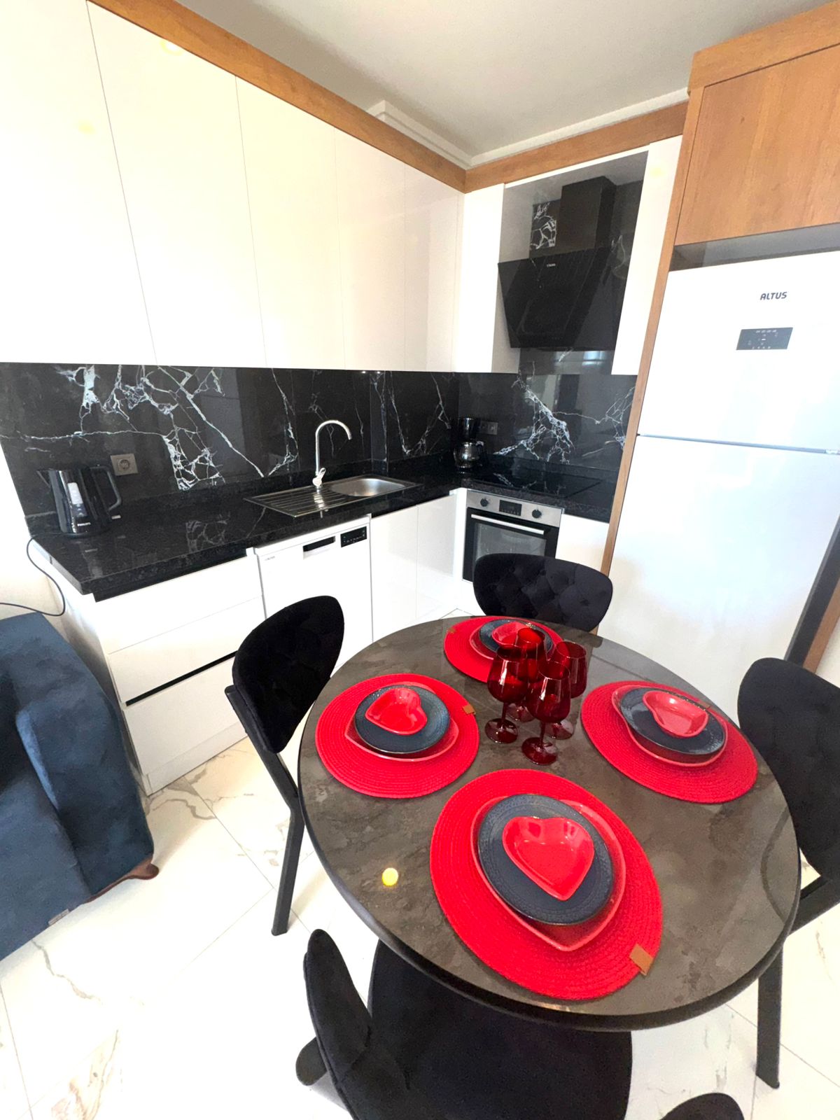 Кухня-гостиная с круглым столом, белым гарнитуром и встроенной духовкой в апартаментах