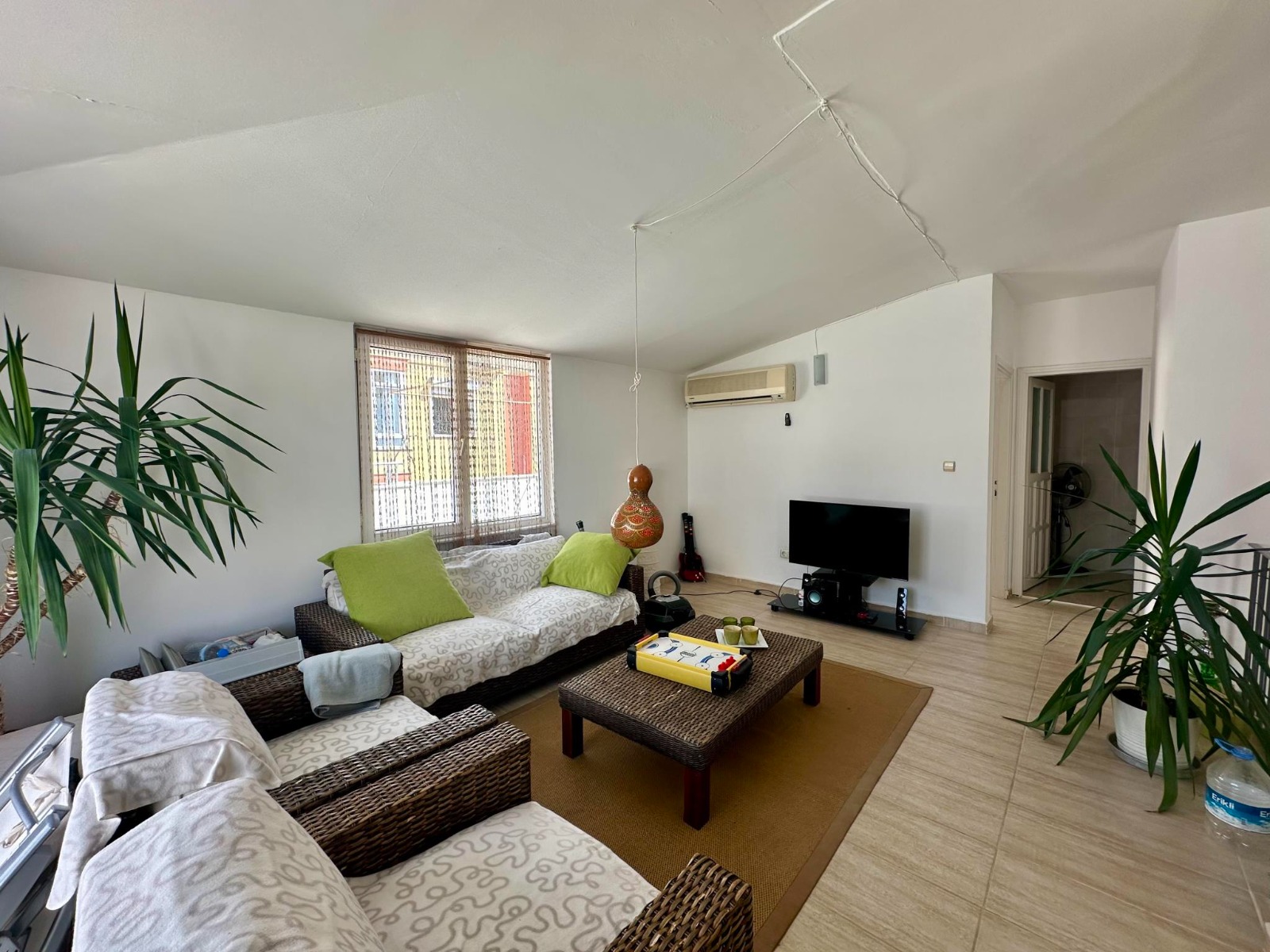 Green cushions, woven armchairs and a panoramic window shape the living room in Turkey