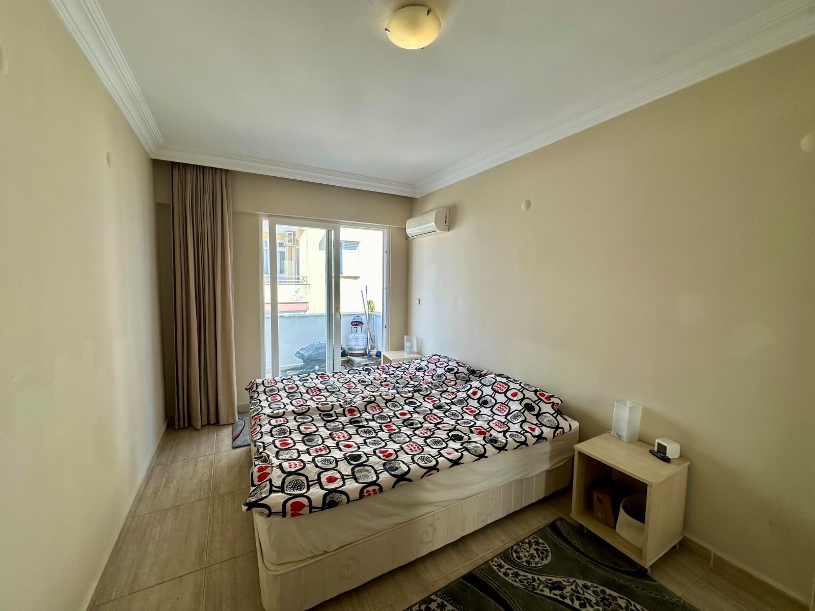 A double bed, heavy curtains and a sliding door furnish the bedroom of a 4+1 penthouse