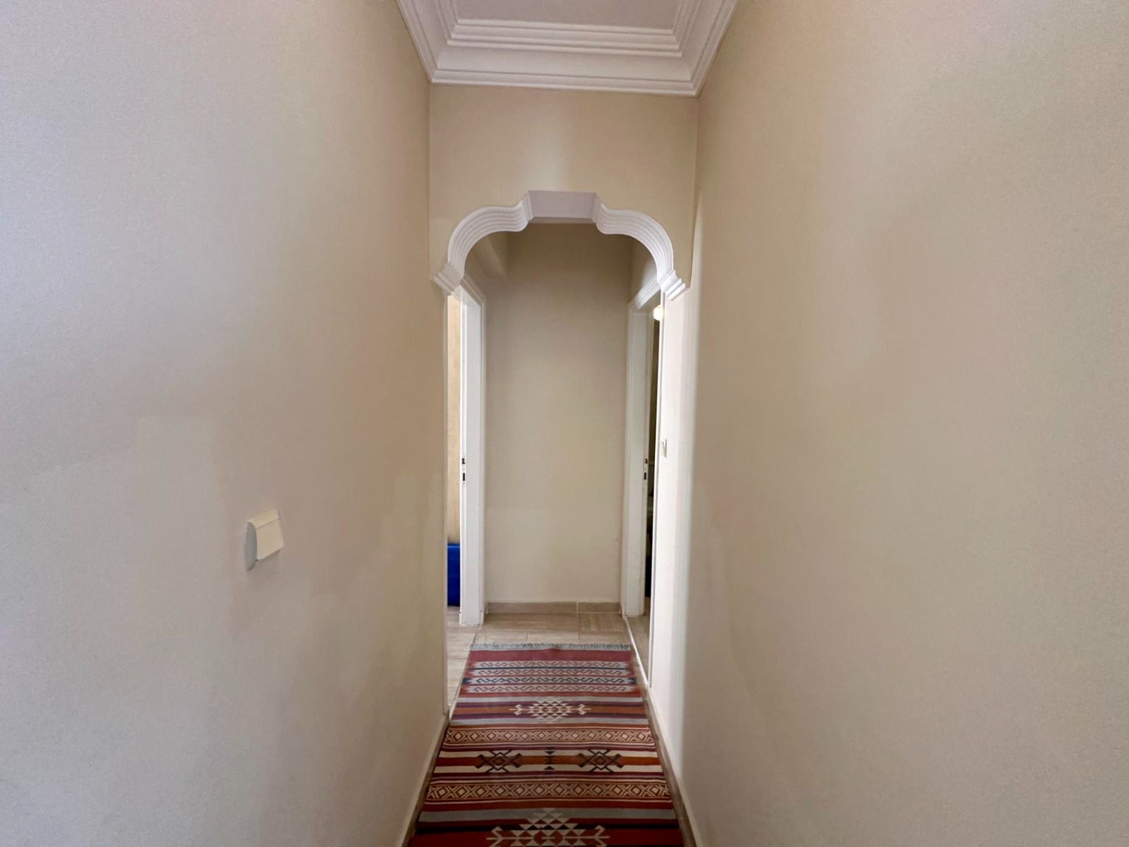 A narrow corridor with a decorative arch and moulding leads through a top-floor apartment in Alanya