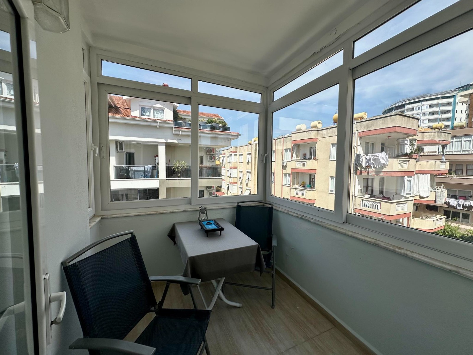 Panoramic glazing and a table with two chairs furnish the enclosed terrace of a penthouse for sale in Turkey