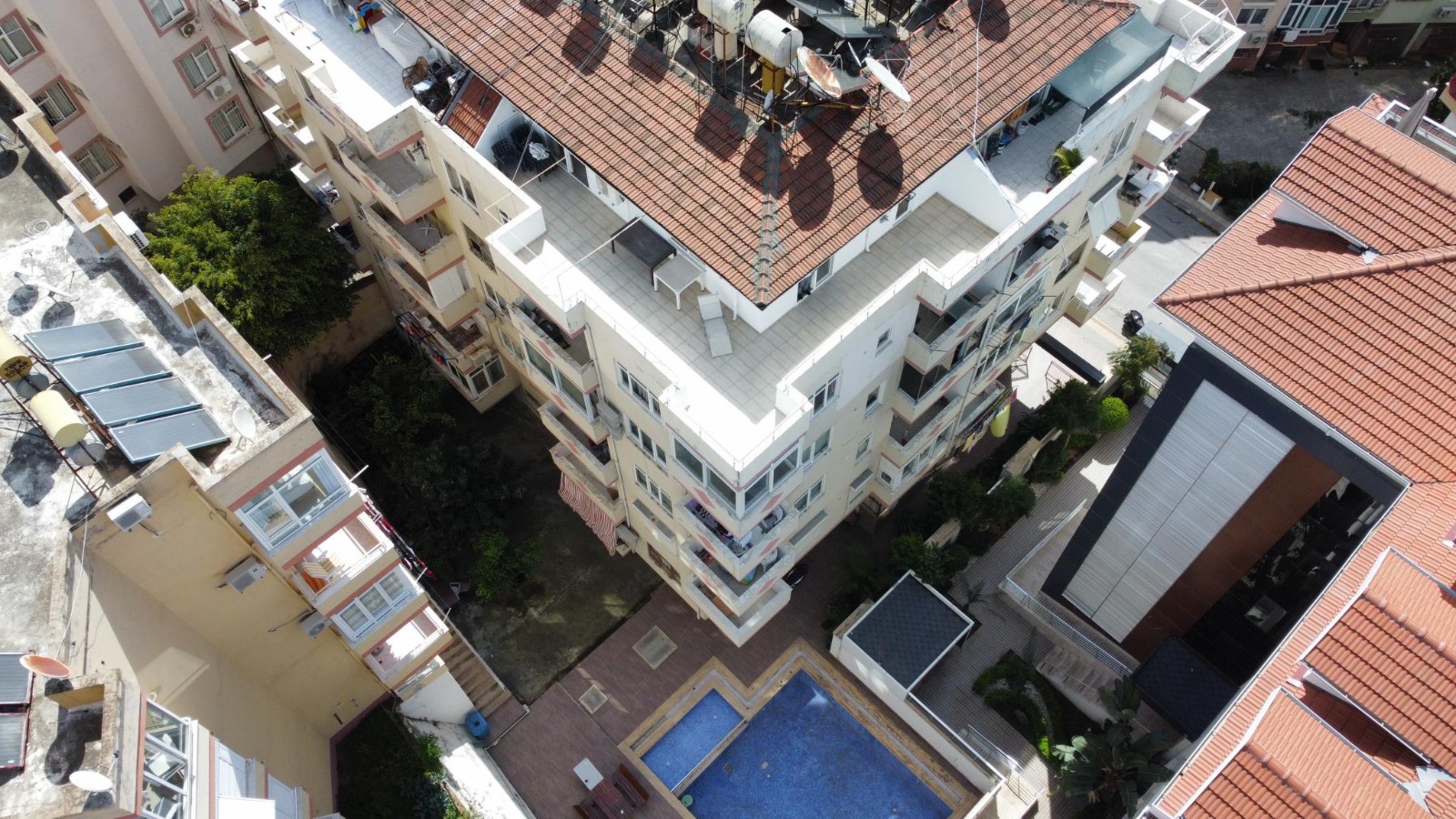Aerial view of an outdoor pool in a tiled courtyard among white buildings in Alanya for sale