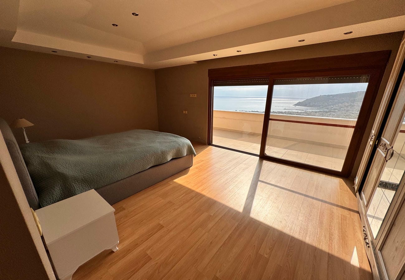 Çift kişilik yataklı odadan balkon camlarıyla görünen deniz, Alanya’da