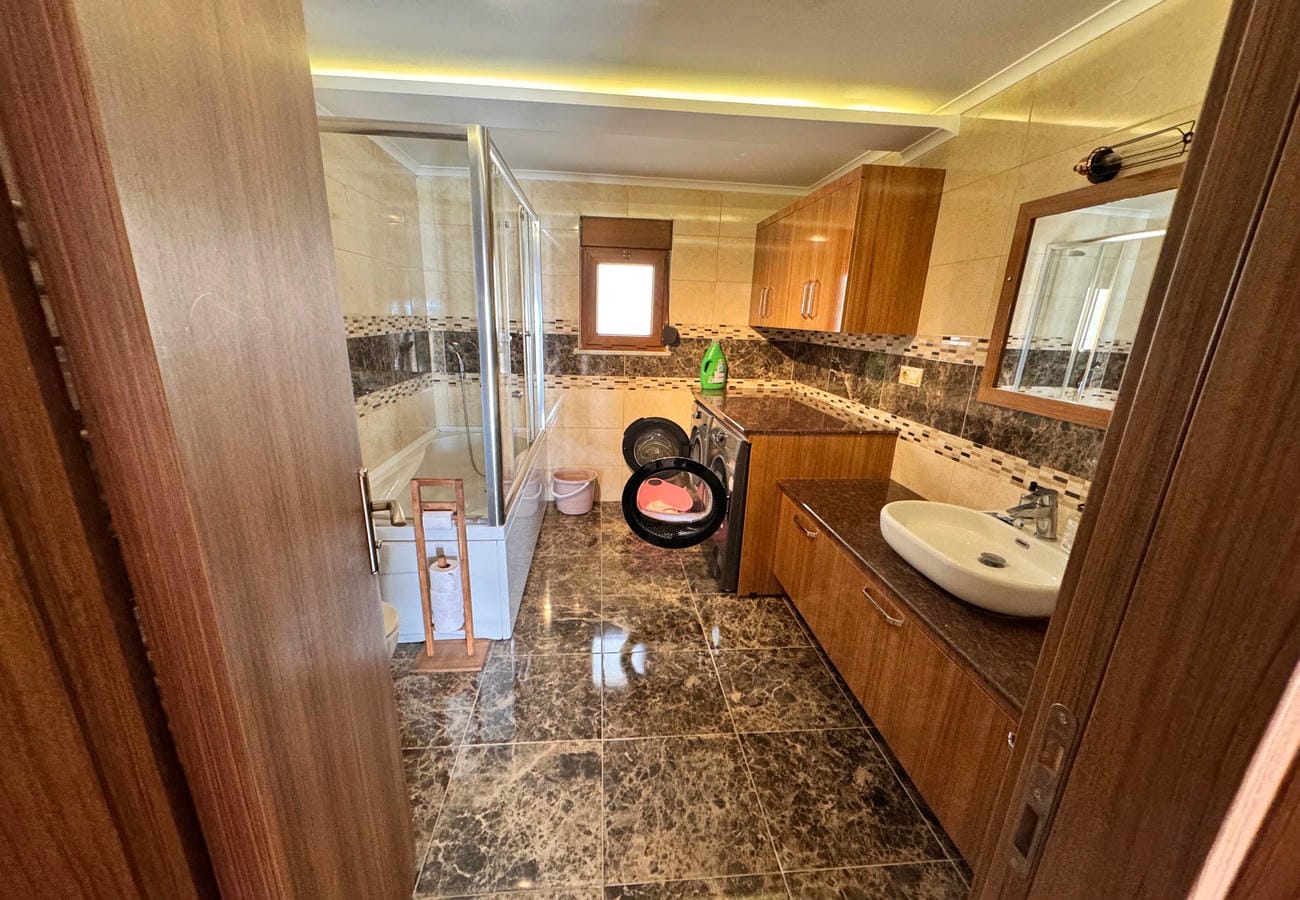 3+1 dairenin banyosunda cam duşakabin, oval lavabo ve koyu mermer zemin