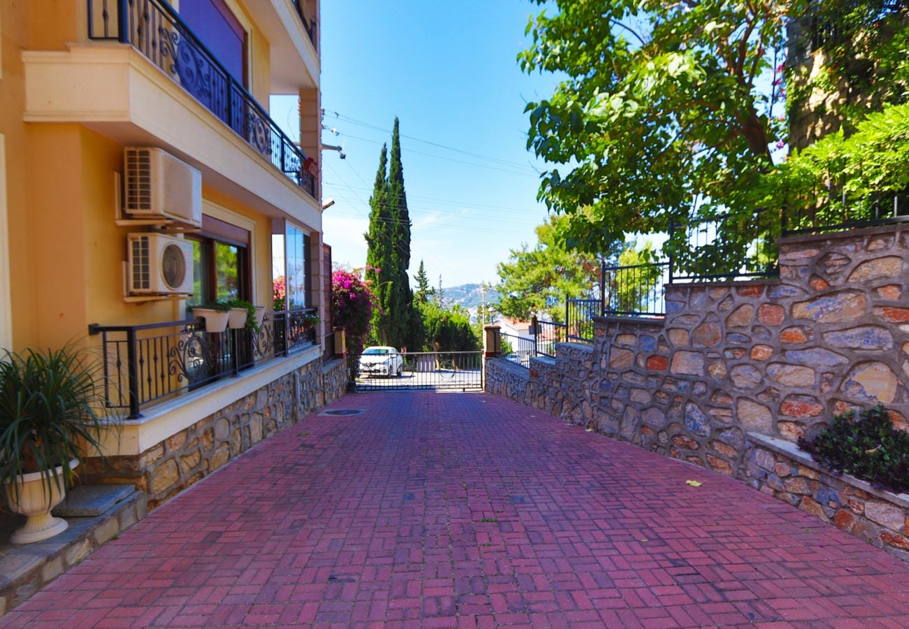 Giriş kapısına uzanan kırmızı parke yol, Alanya’daki apartman dairelerinin yanında