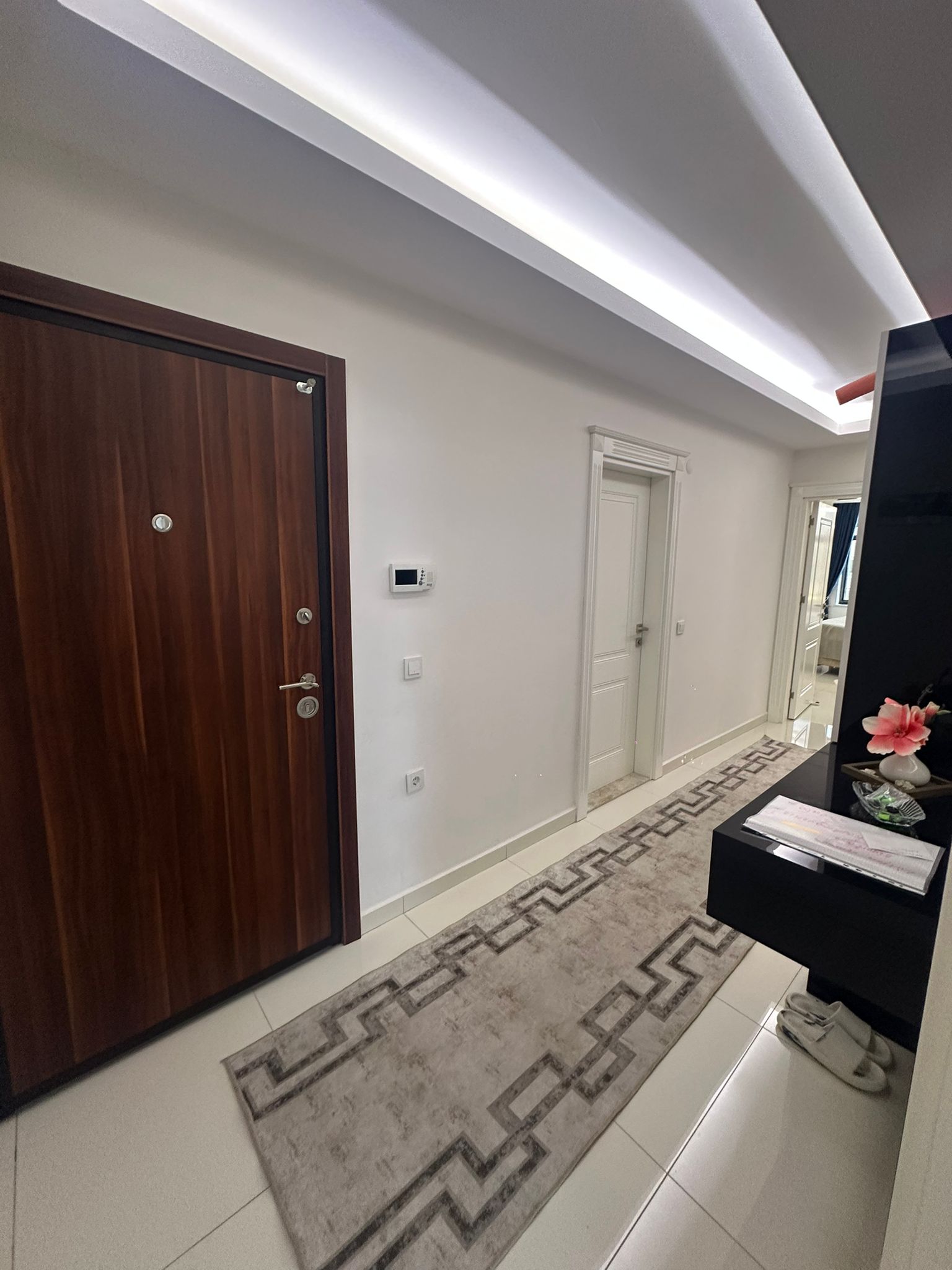 Antrede siyah beyaz konsol, yüksek duvar aynası ve parlak beyaz fayans zemin