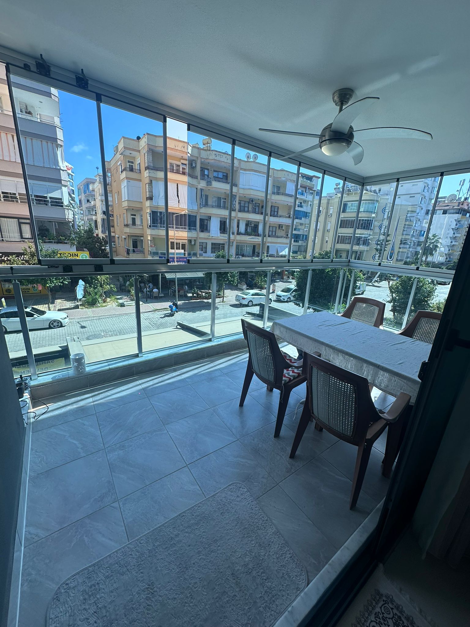 Mahmutlar’da satılık dairenin köşe balkonunda panoramik camlar ve beyaz örtülü yemek masası