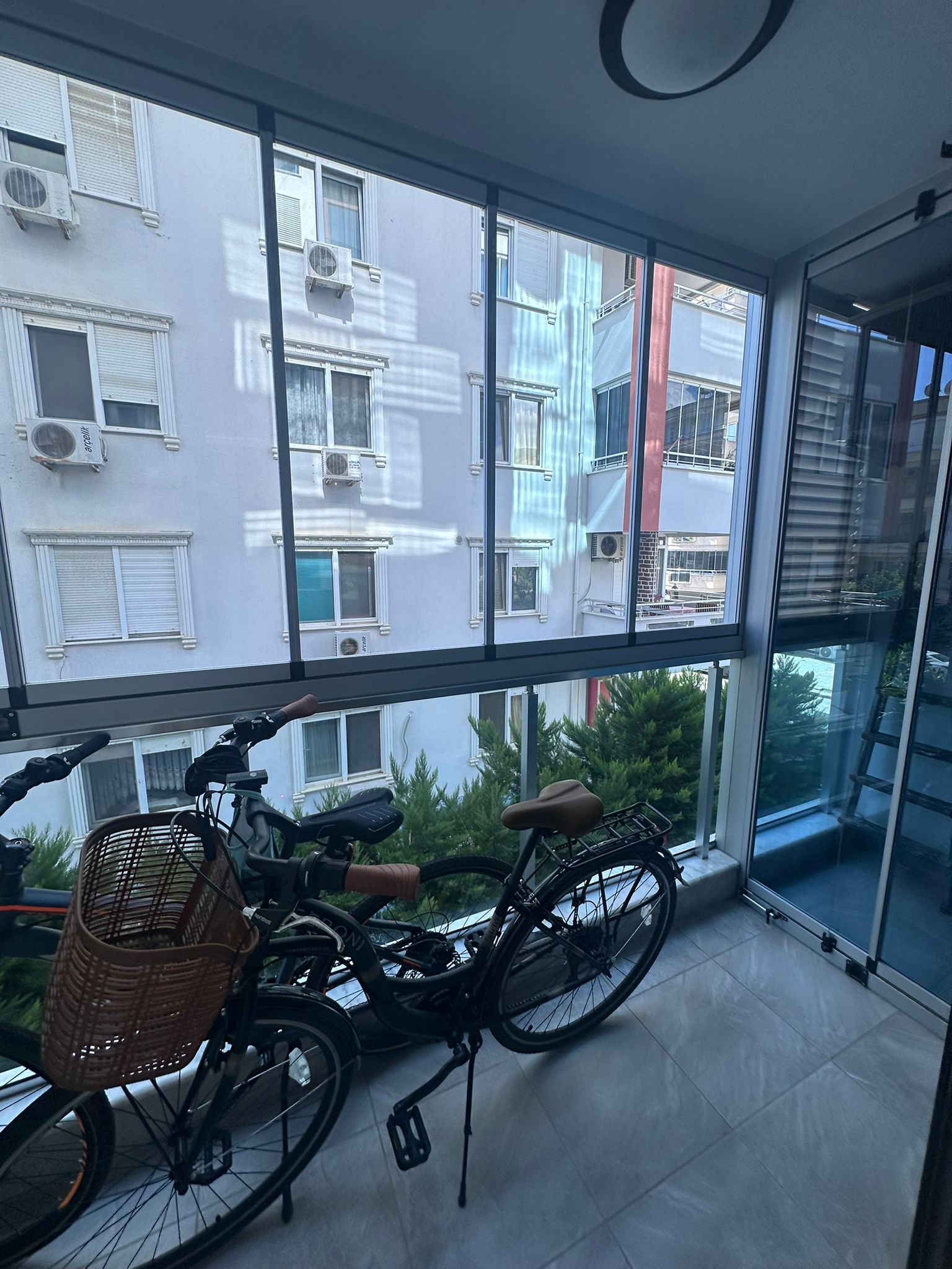 Türkiye’de satılık dairenin camlı balkonunda iki bisiklet ve panoramik sürgülü camlar