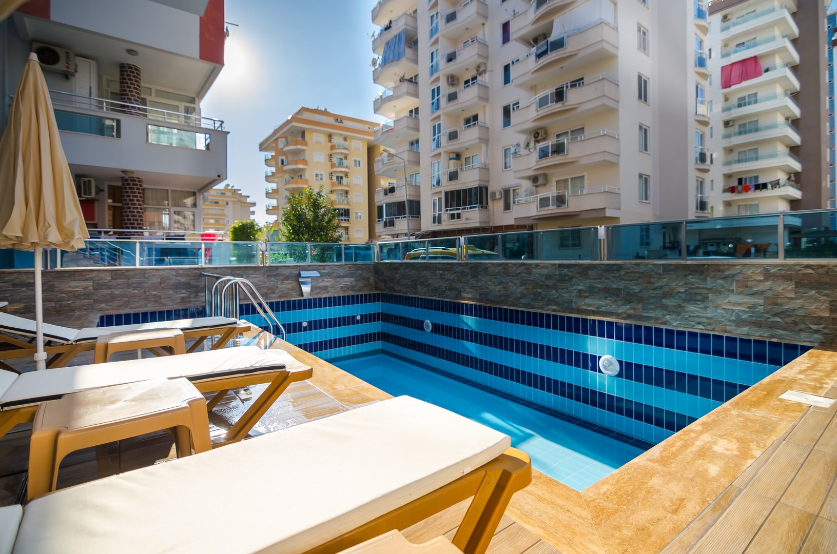 Alanya’da rezidans sakinleri için açık havuzda mavi mozaik kaplama ve kapalı şemsiye, Türkiye’de