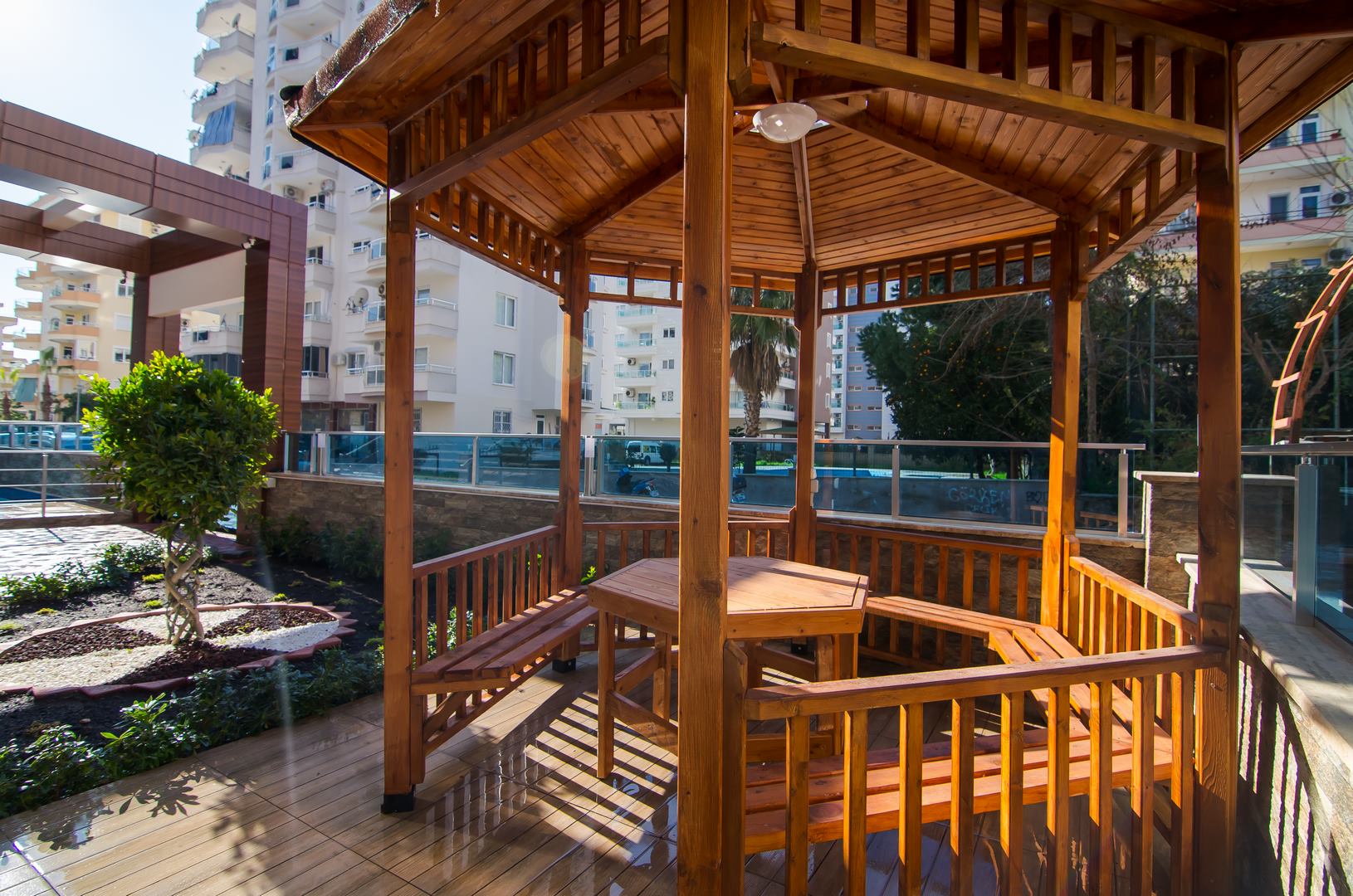 Alanya’da kompleks bahçesindeki ahşap kameriye, sabit banklar ve masa ile Türkiye’de